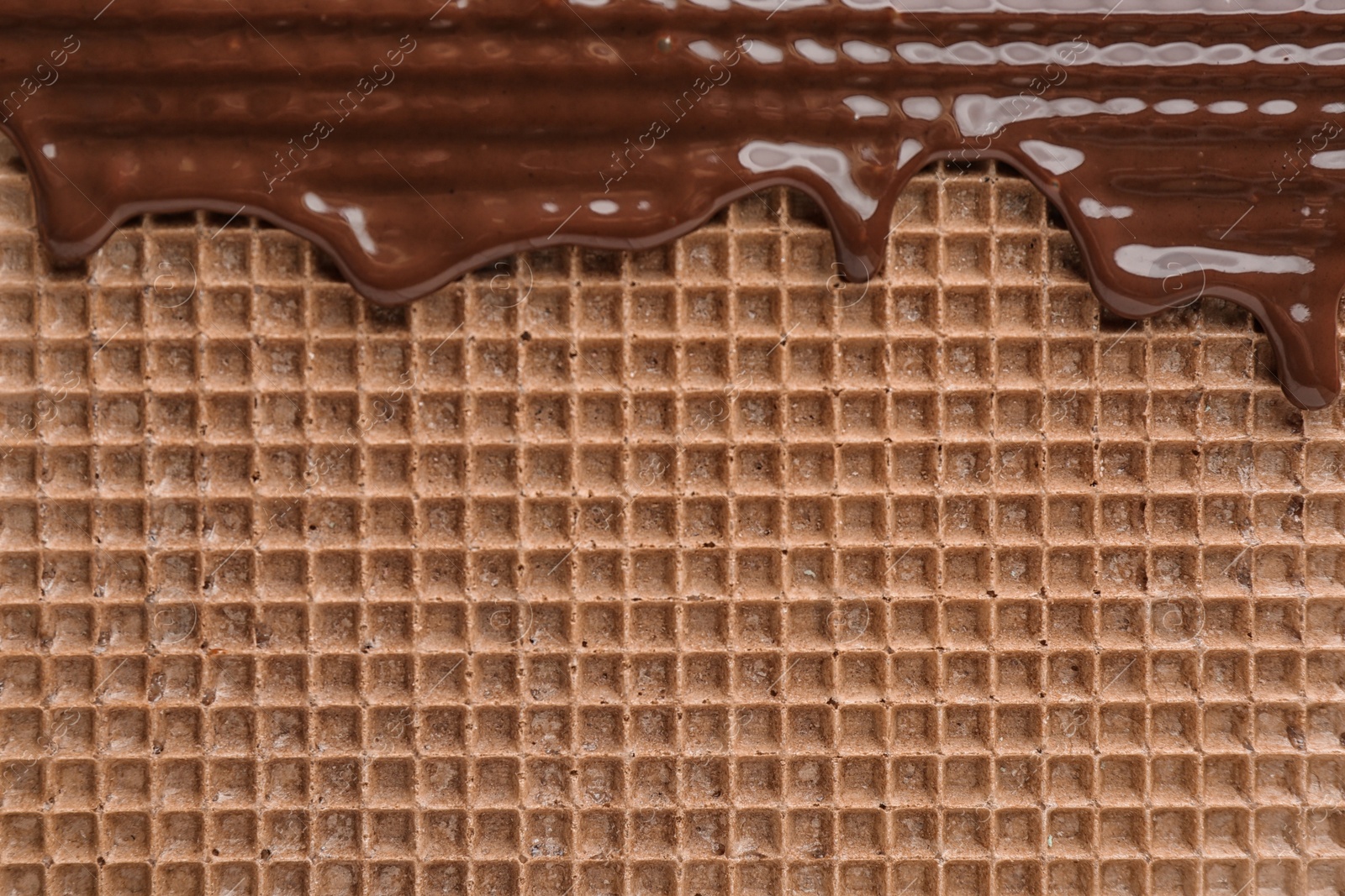 Photo of Hot dark chocolate on wafer, closeup. Crispy food