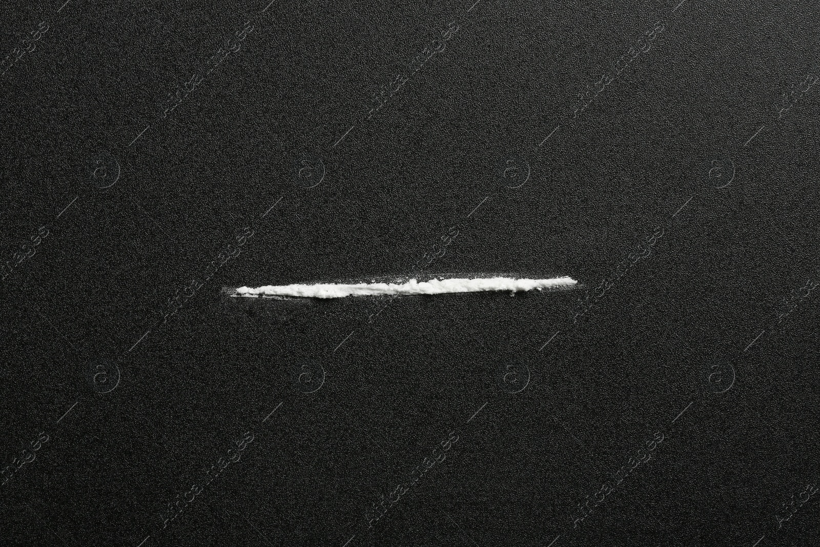 Photo of Line of cocaine on dark background, top view