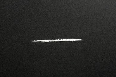 Photo of Line of cocaine on dark background, top view