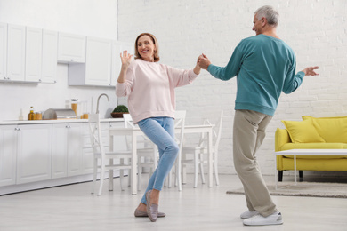 Photo of Happy senior couple dancing together in kitchen