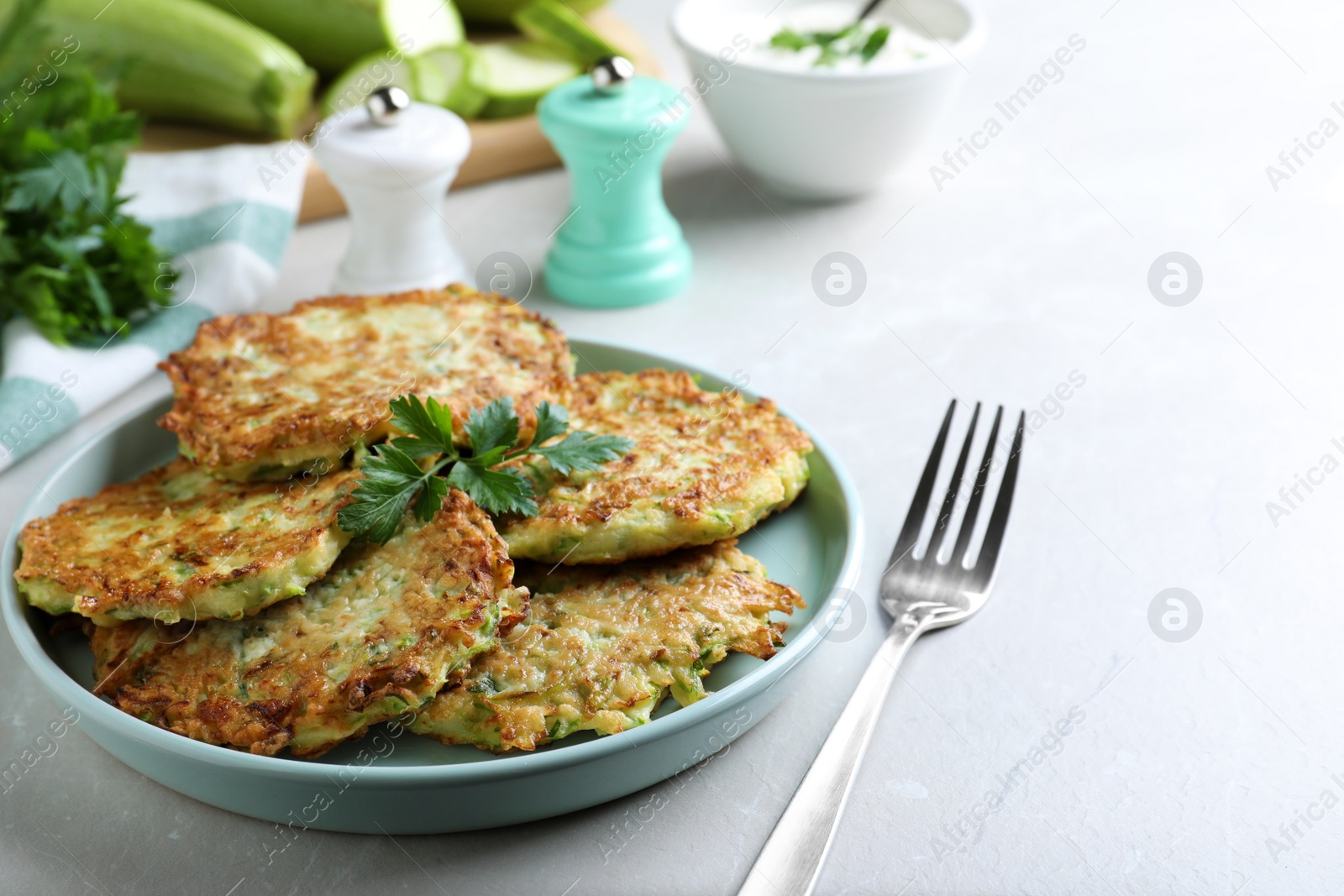 Photo of Delicious zucchini fritters served on light table, closeup