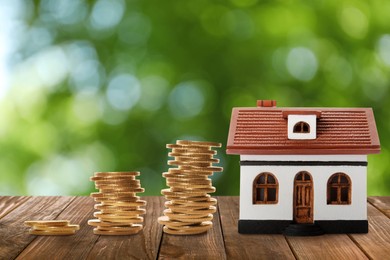 Image of Real estate investing. House model and coins on wooden table