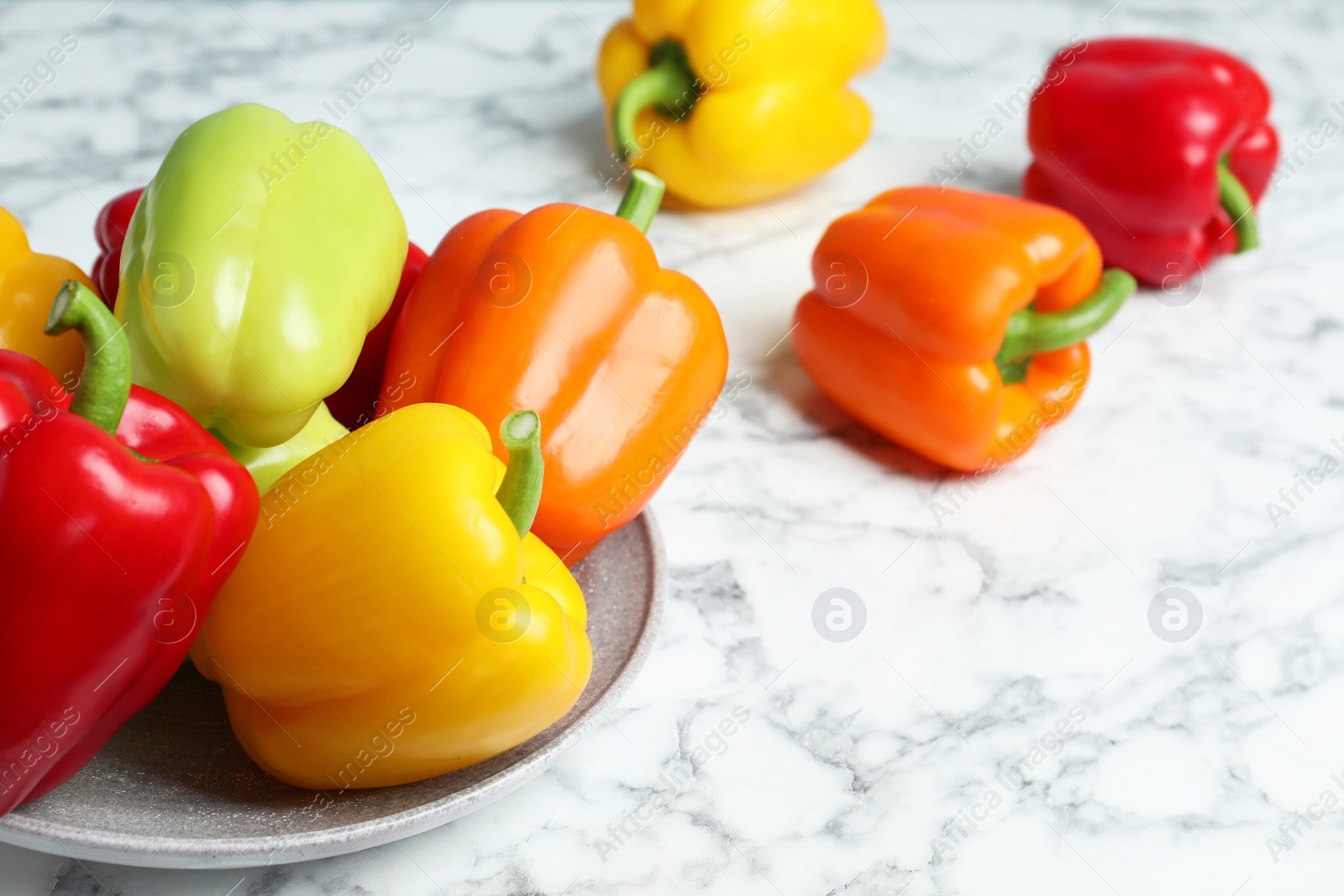 Photo of Plate with ripe bell peppers on marble table