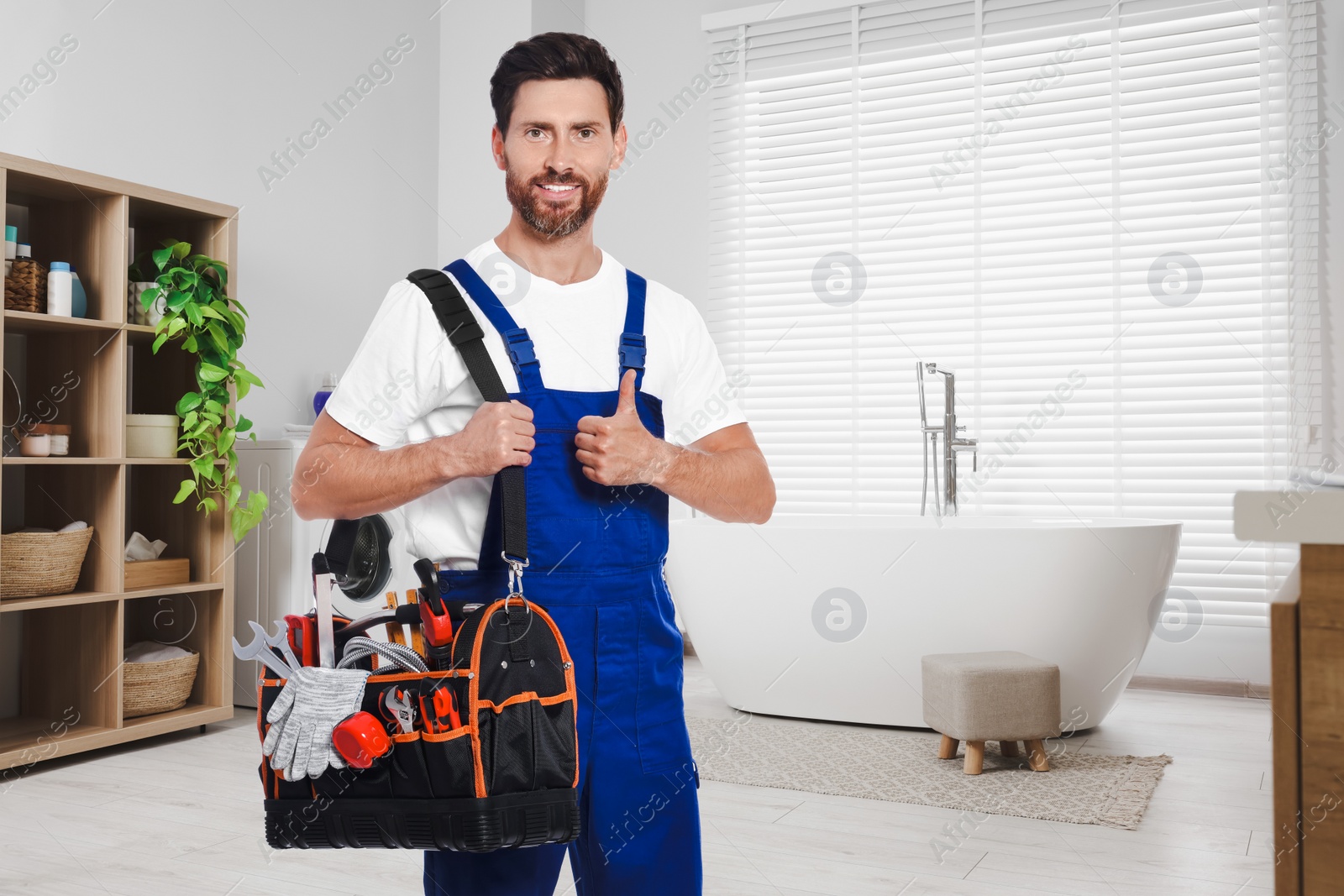 Image of Plumber with bag of instruments showing thumbs up in bathroom, space for text