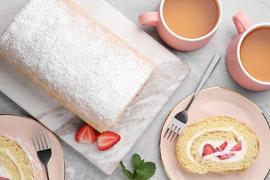 Photo of Delicious sponge cake roll with strawberries and cream served on light grey table, flat lay