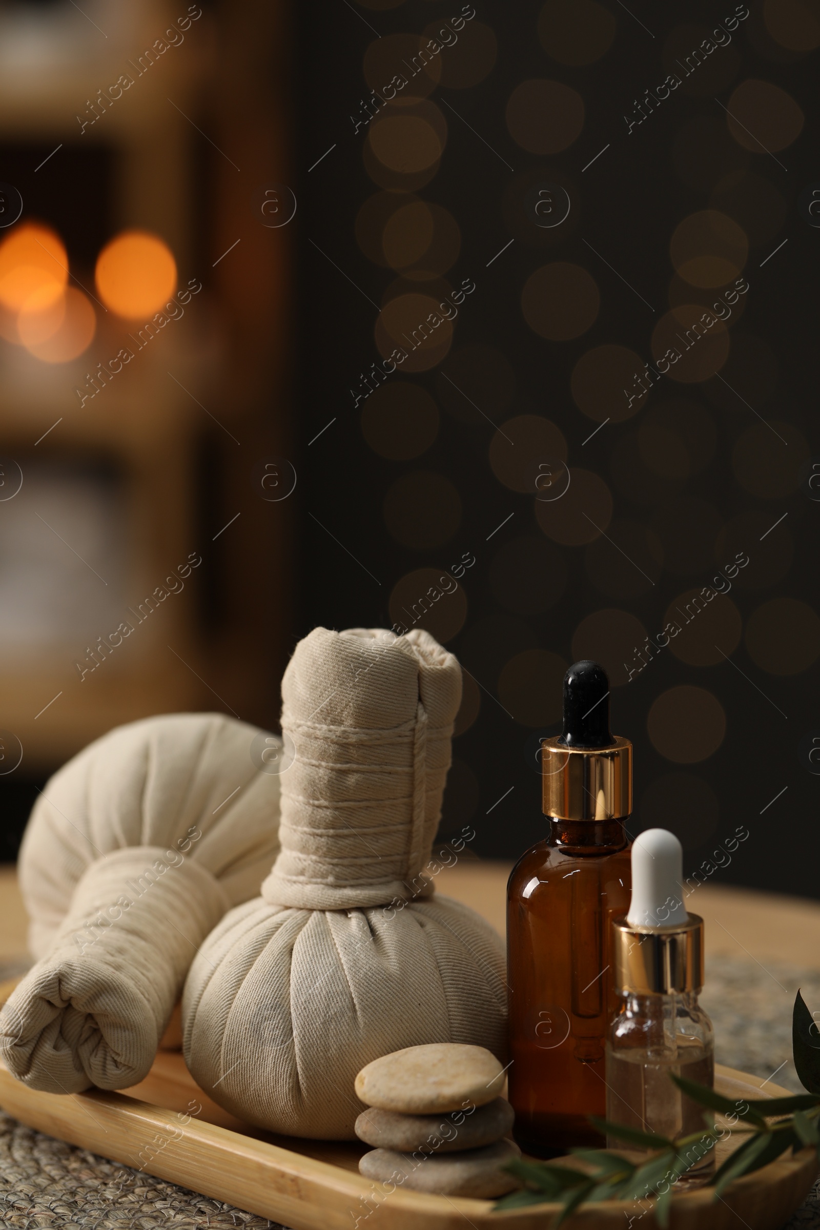 Photo of Spa composition. Herbal sacks, cosmetic products and stones on table indoors. Space for text