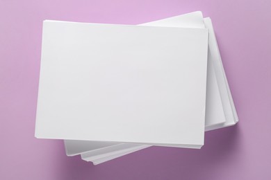 White paper sheets on violet background, top view