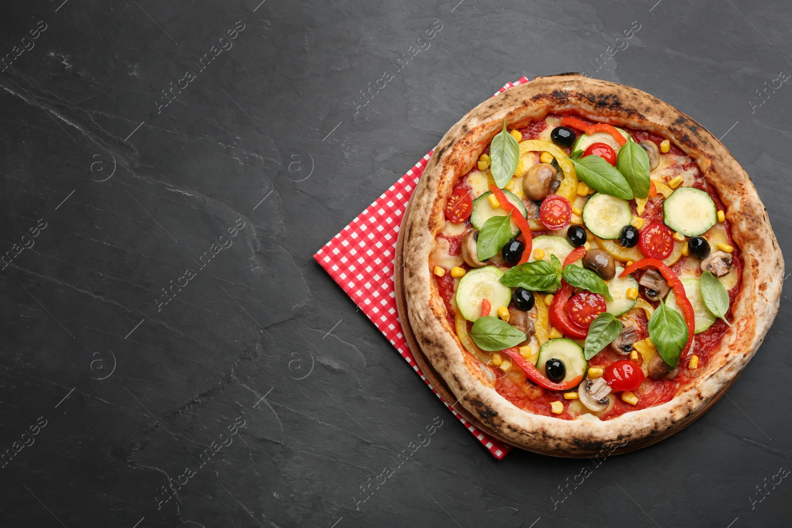 Photo of Delicious hot vegetable pizza on black table, top view. Space for text