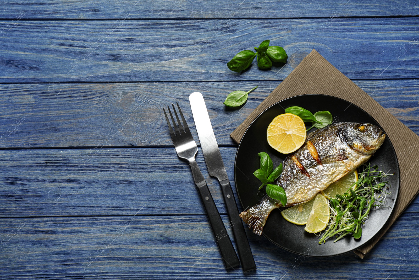 Photo of Delicious roasted fish with lemon on blue wooden table, flat lay. Space for text
