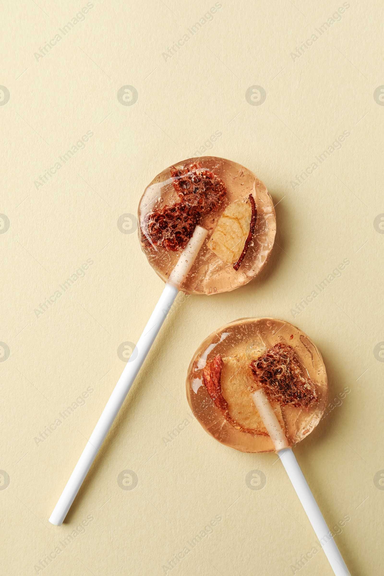 Photo of Sweet colorful lollipops with berries on beige background, flat lay