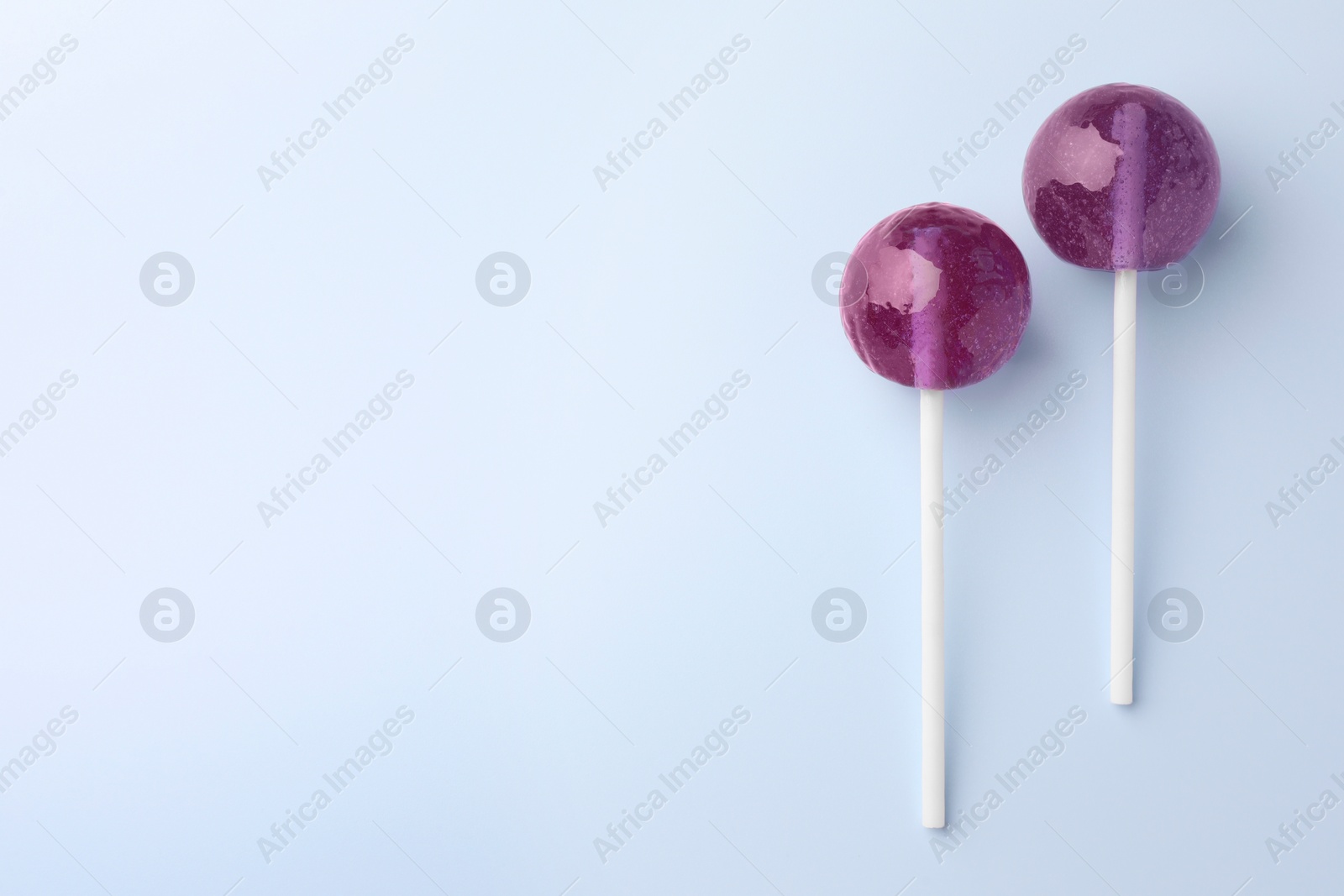 Photo of Tasty lollipops on light blue background, flat lay. Space for text