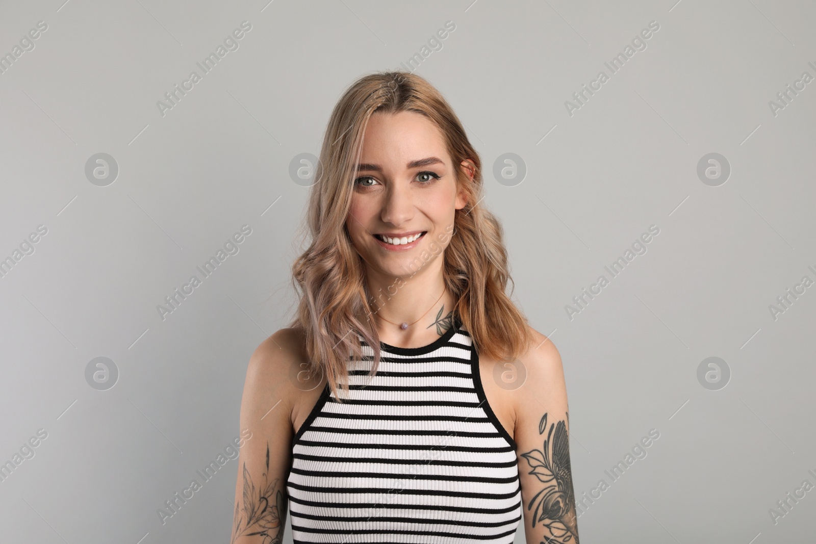 Photo of Beautiful woman with tattoos on body against grey background