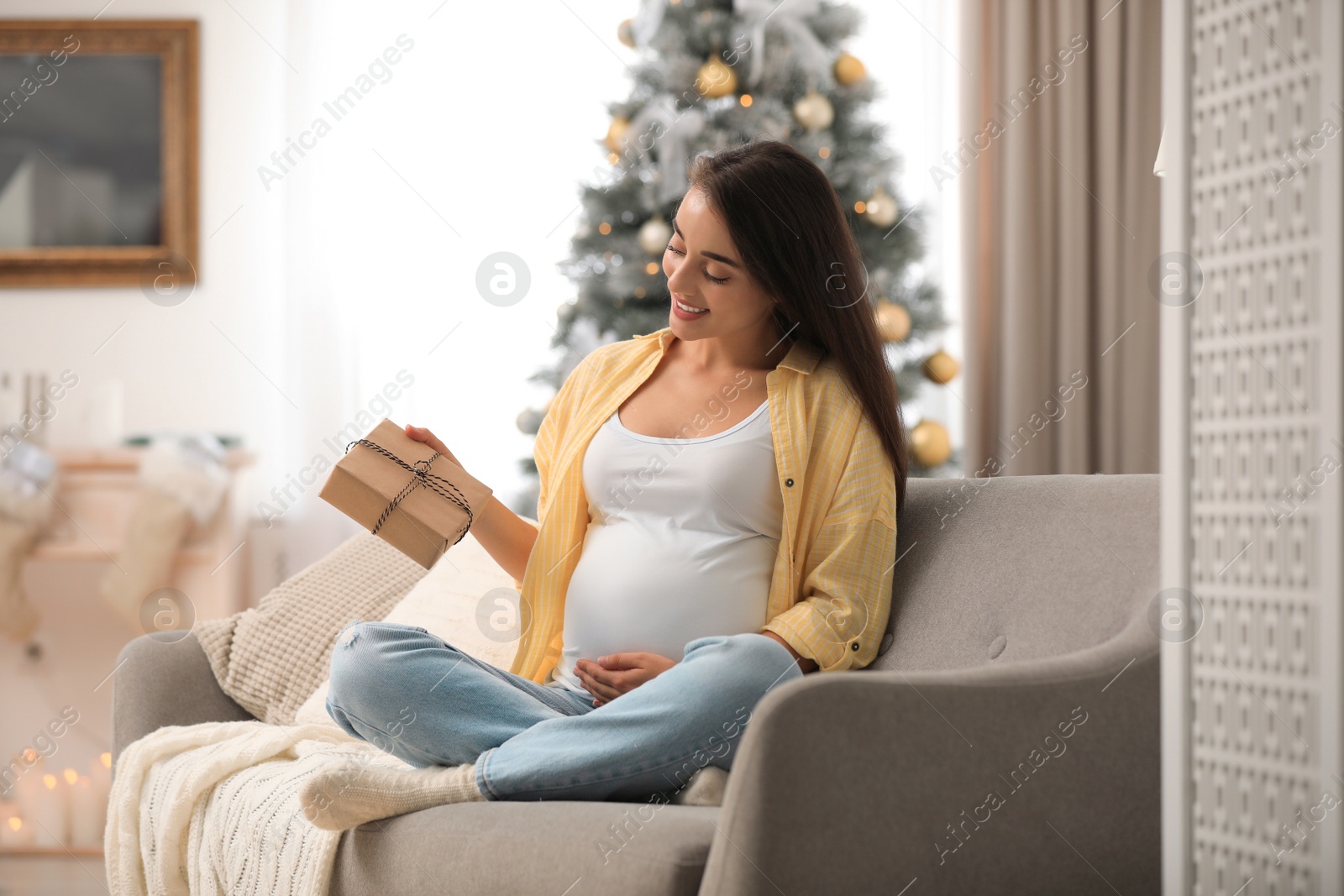 Photo of Happy pregnant woman with Christmas gift box at home. Expecting baby