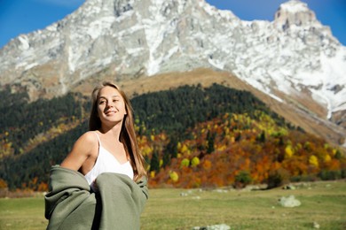 Young woman walking in beautiful mountains on sunny day. Space for text