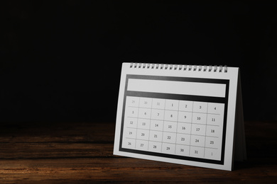 Photo of Paper calendar on wooden table, space for text. Planning concept