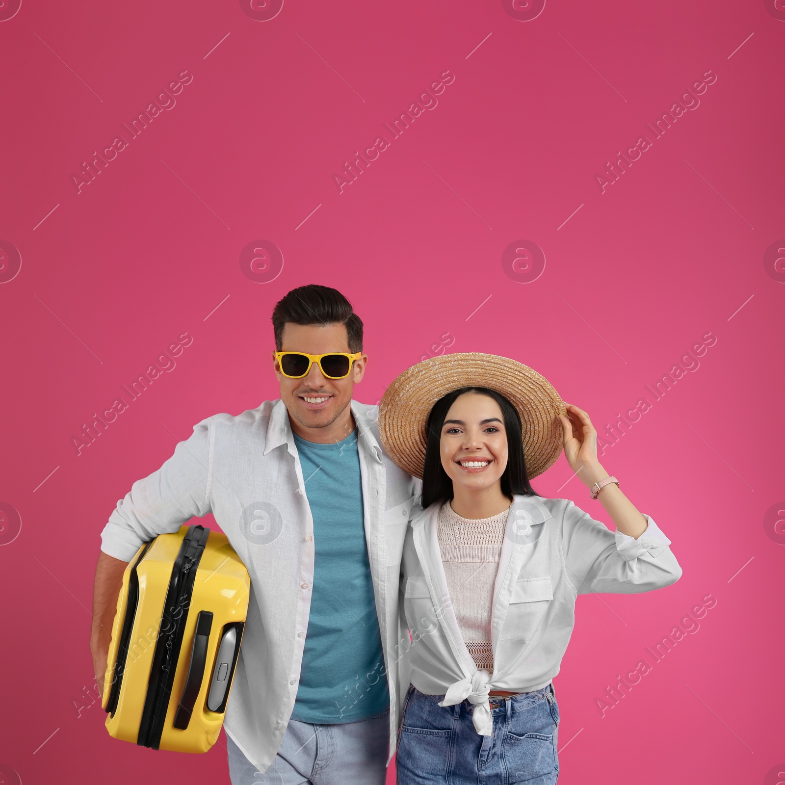 Photo of Couple of tourists with suitcase on pink background