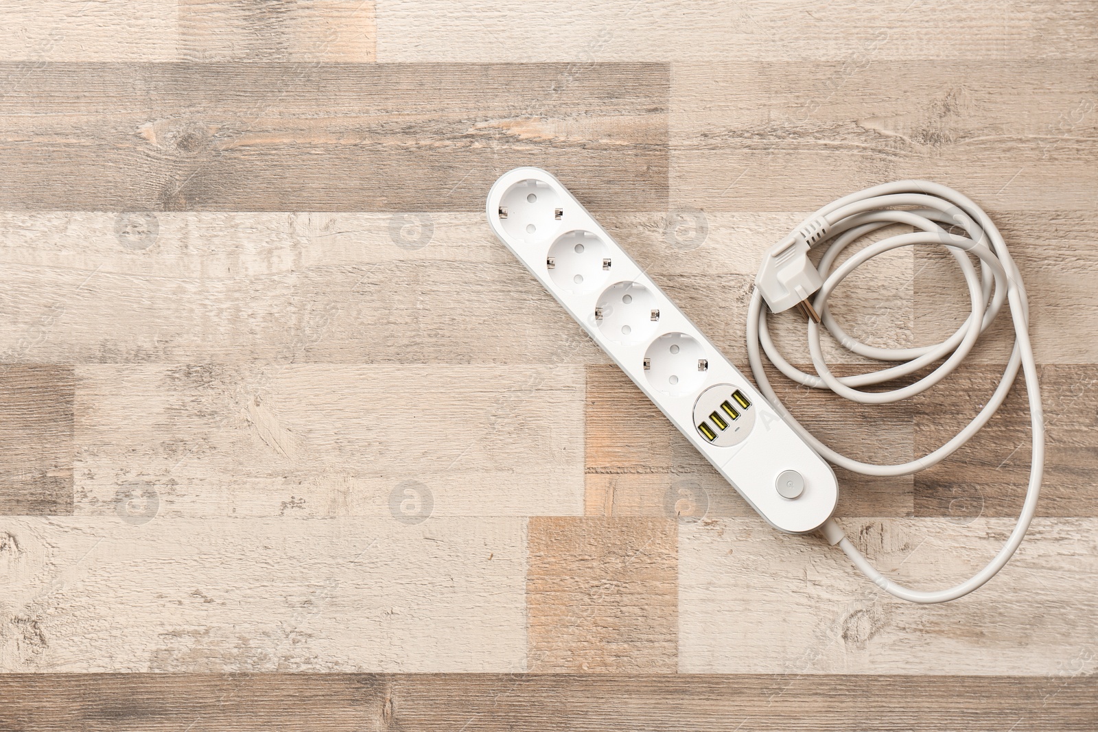 Photo of Extension cord on wooden floor, top view with space for text. Electrician's equipment