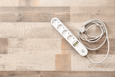 Extension cord on wooden floor, top view with space for text. Electrician's equipment