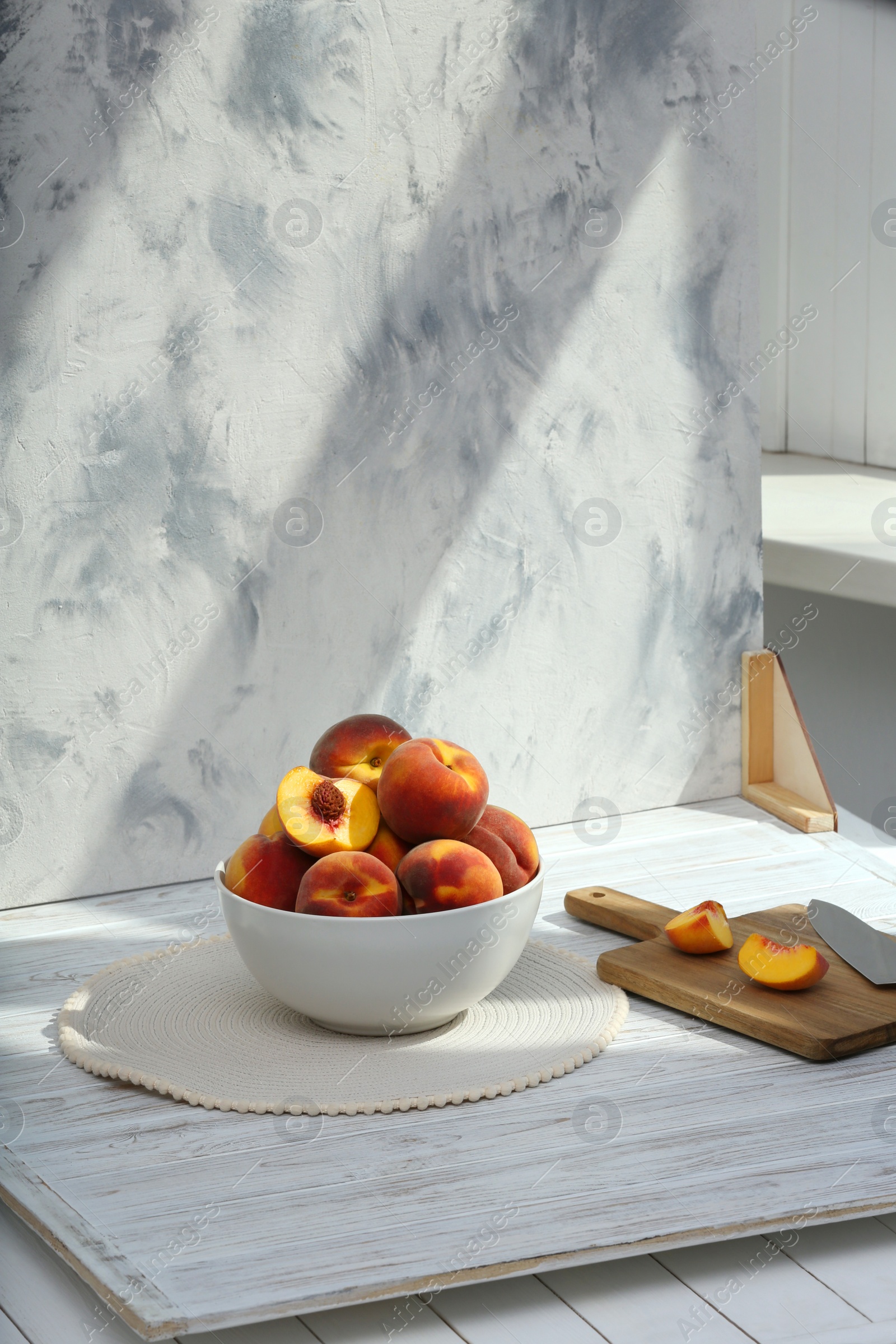 Photo of Bowl of juicy peaches and double-sided backdrop on table in photo studio