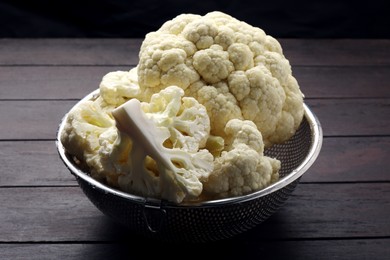 Photo of Colander with fresh raw cauliflower on wooden table