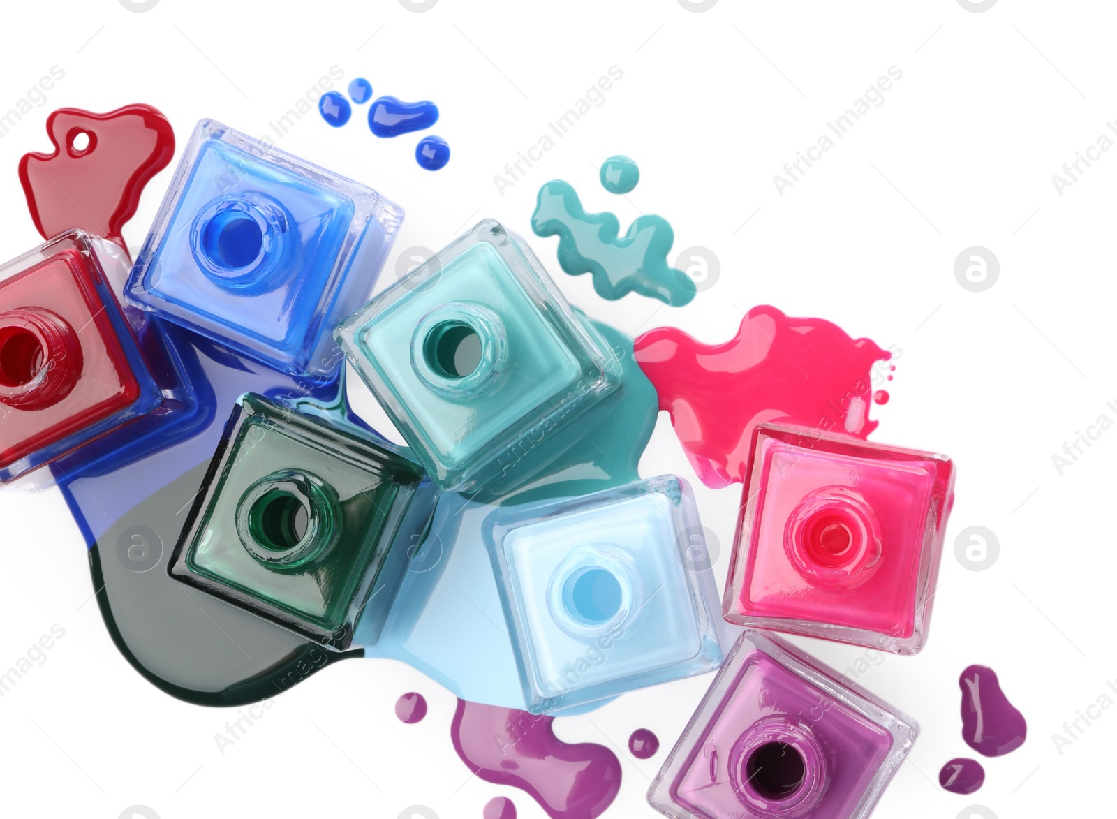 Photo of Drops of different bright nail polishes and bottles isolated on white, top view