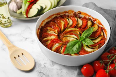 Delicious ratatouille and ingredients on white marble table