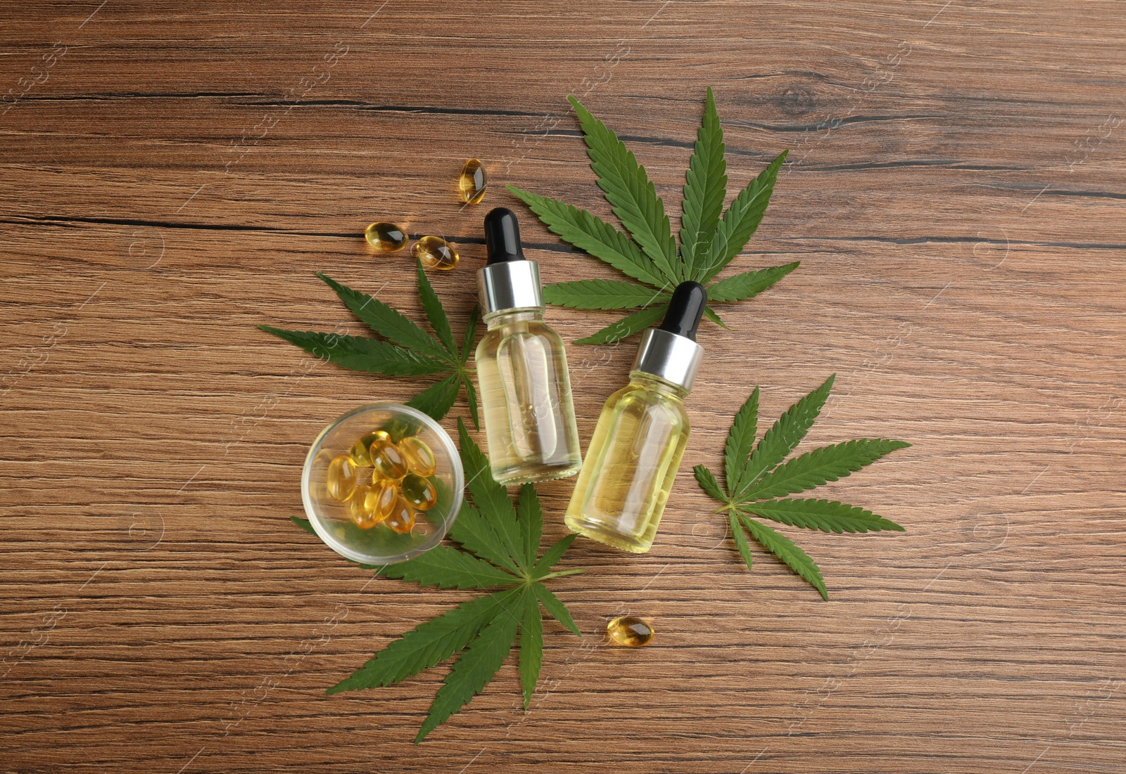 Photo of Composition with CBD oil, THC tincture and hemp leaves on wooden table, flat lay