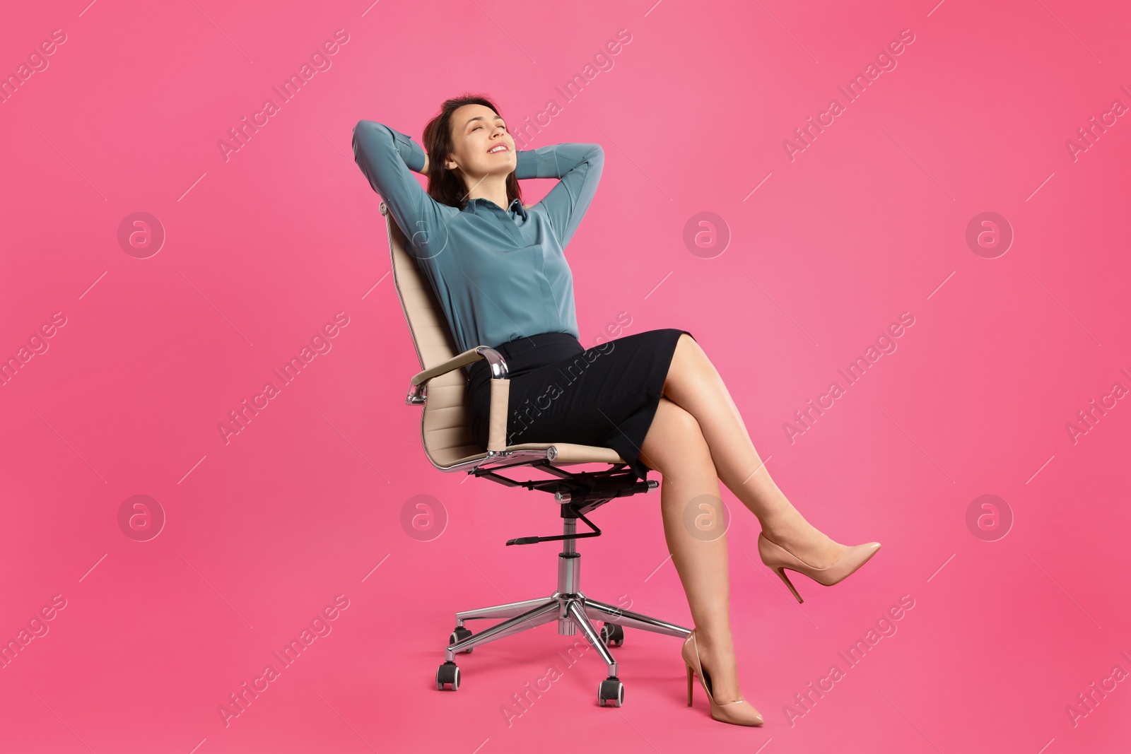 Photo of Mature businesswoman relaxing in comfortable office chair on pink background