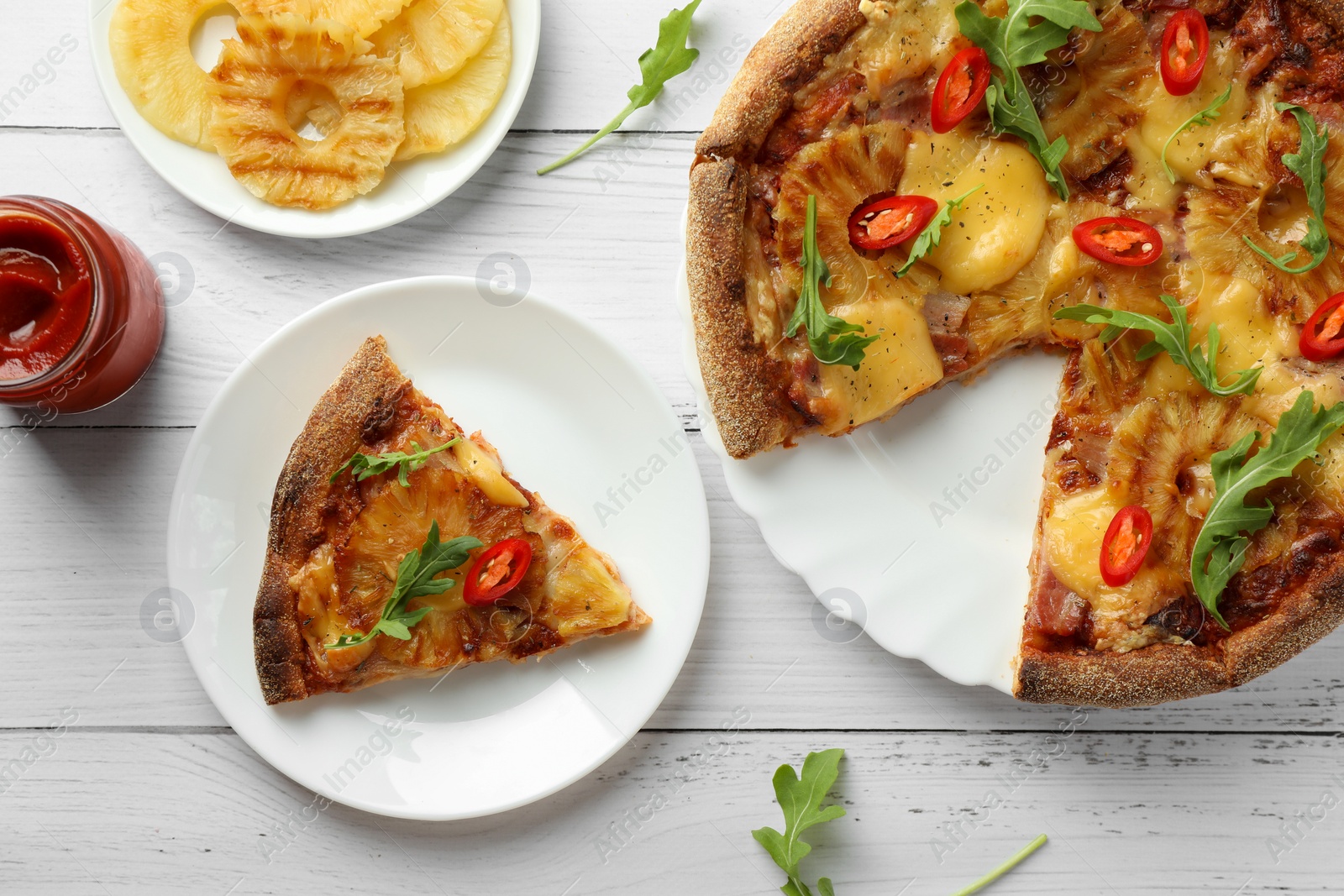 Photo of Delicious Hawaiian pizza with pineapple and ingredients on white wooden table, flat lay