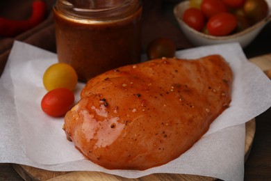Photo of Fresh marinade and raw chicken fillets on wooden table, closeup