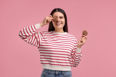 Young woman with chocolate chip cookies on pink background