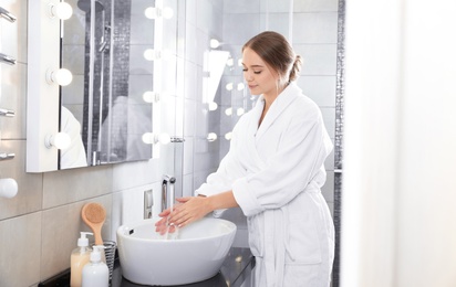 Photo of Young woman washing hands in bathroom. Using soap