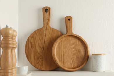 Photo of Wooden cutting boards and shakers on white shelf