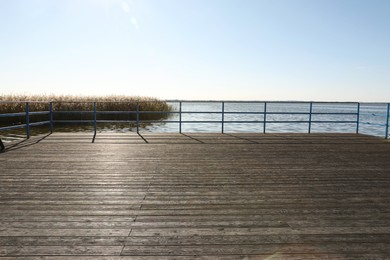 Photo of Beautiful view of wooden terrace with railing near river on sunny day