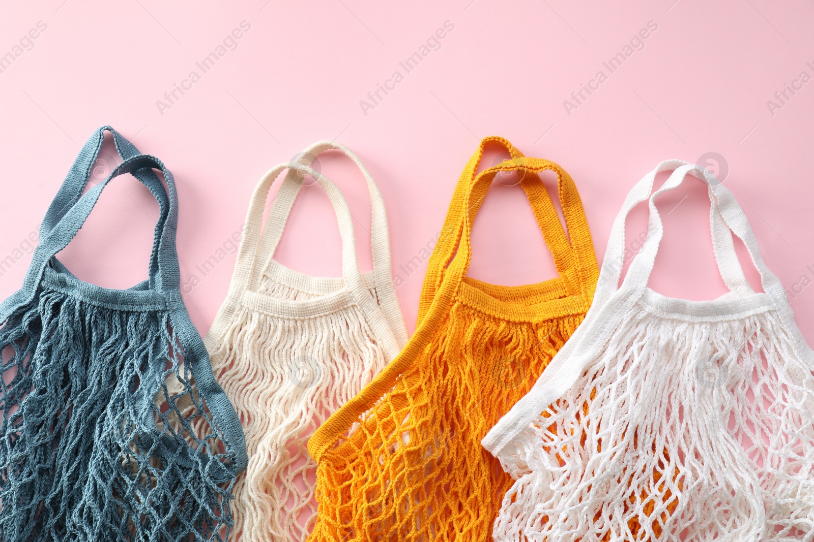 Photo of Different string bags on pink background, top view