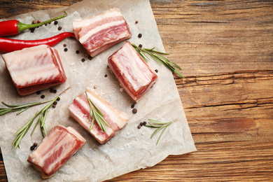 Raw ribs with rosemary and spices on wooden table, flat lay