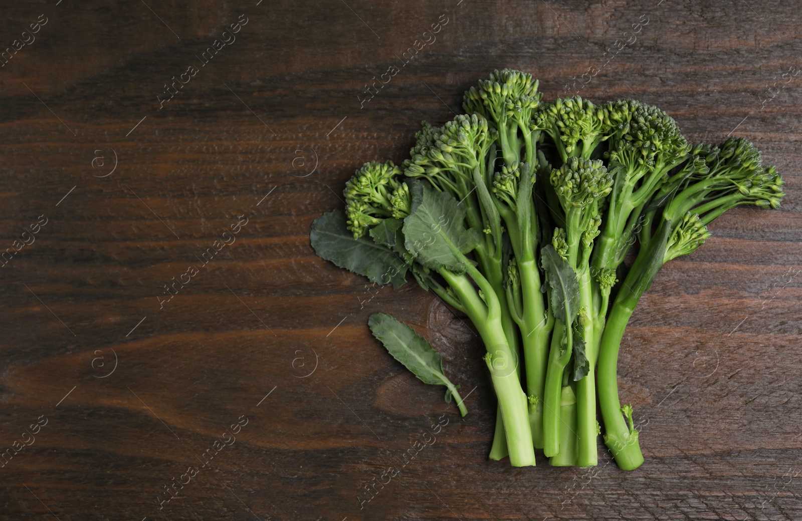 Photo of Fresh raw broccolini on wooden table, flat lay and space for text. Healthy food