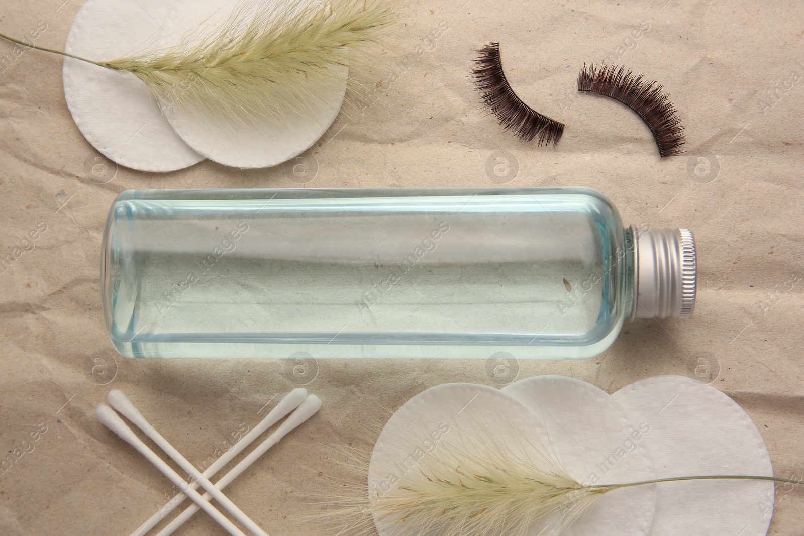 Photo of Flat lay composition with makeup remover and false eyelashes on crumpled paper