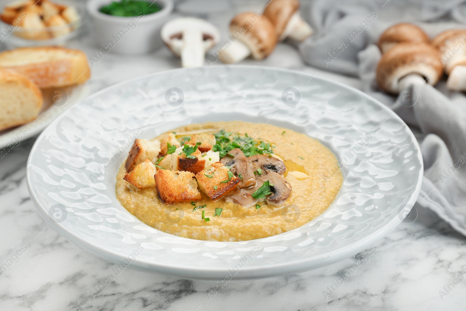 Photo of Delicious cream soup with mushrooms and croutons on white marble table