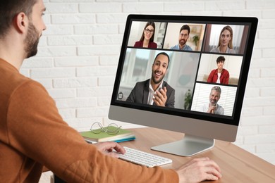 Image of Man having video chat with coworkers at office