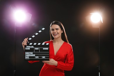 Photo of Happy actress with clapperboard on stage. Film industry