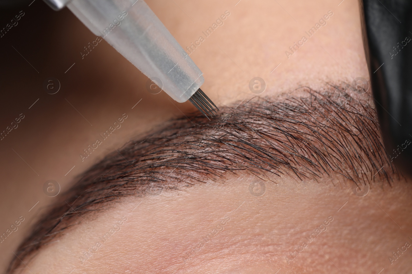 Photo of Young woman during procedure of permanent eyebrow makeup, closeup