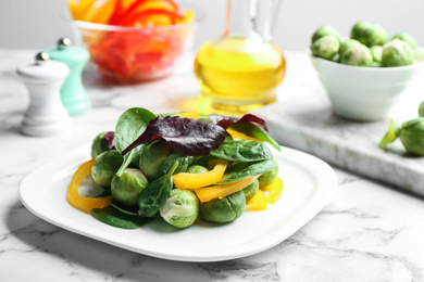 Photo of Tasty salad with Brussels sprouts on white marble table