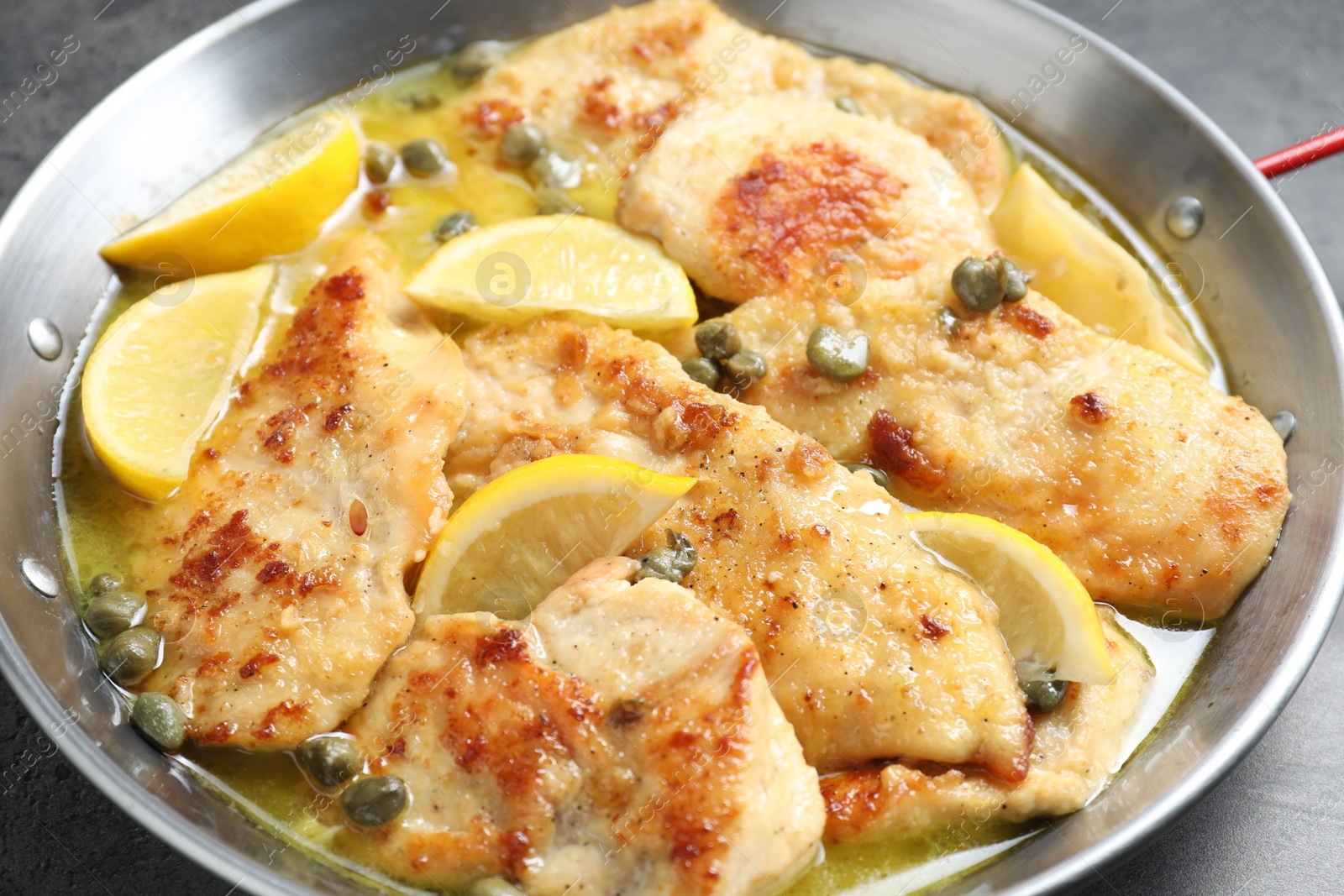 Photo of Delicious chicken piccata with lemons in pot, closeup