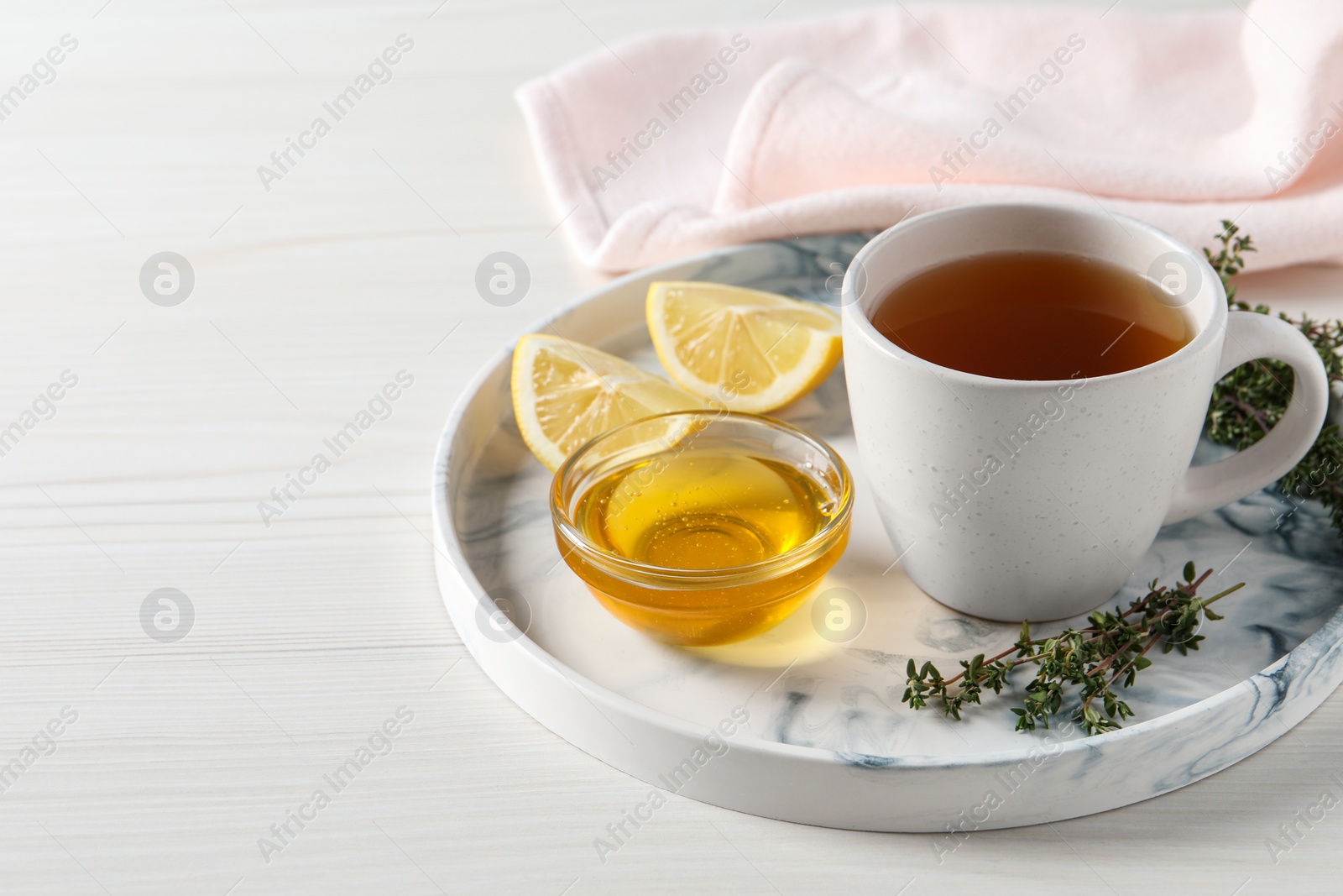 Photo of Aromatic herbal tea with thyme, honey and lemons on white wooden table, space for text