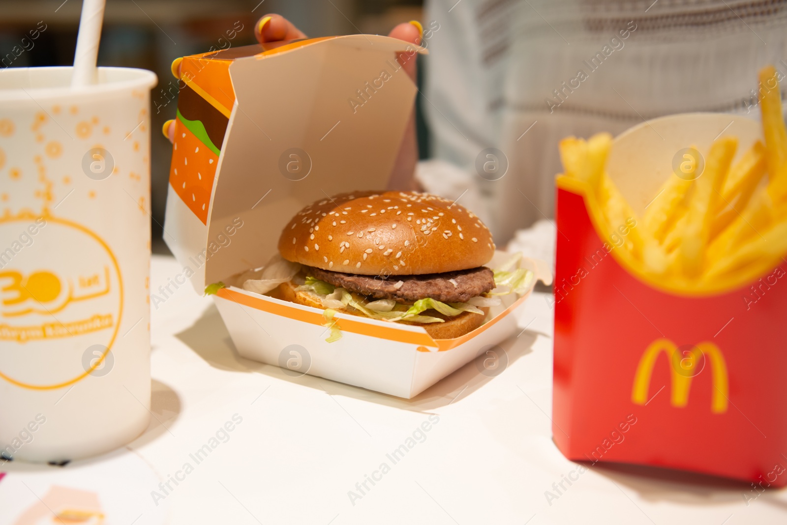 Photo of WARSAW, POLAND - SEPTEMBER 04, 2022: Woman with McDonald's burger, French fries and drink at table in cafe, closeup