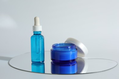 Photo of Bottle and jar with cosmetic products on light background