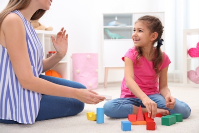 Woman and her child playing together with colorful blocks at home