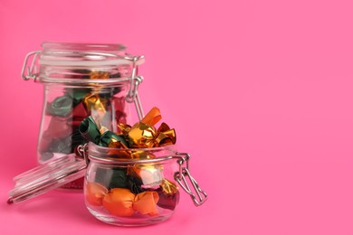 Photo of Candies in colorful wrappers on pink background. Space for text