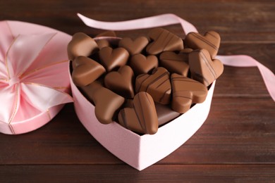 Photo of Beautiful heart shaped chocolate candies in box on wooden table